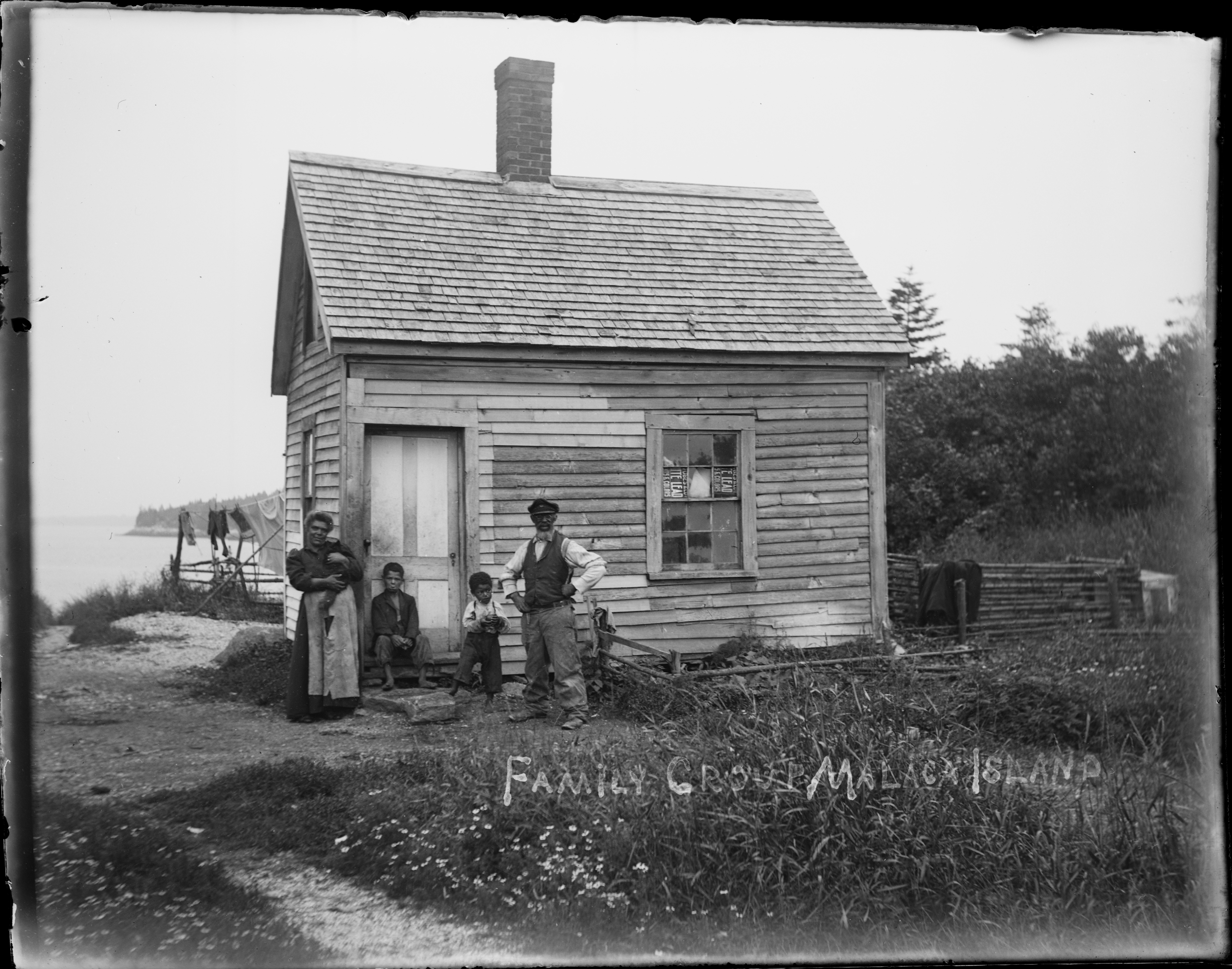 Old wooden shed with a family of four standing in front