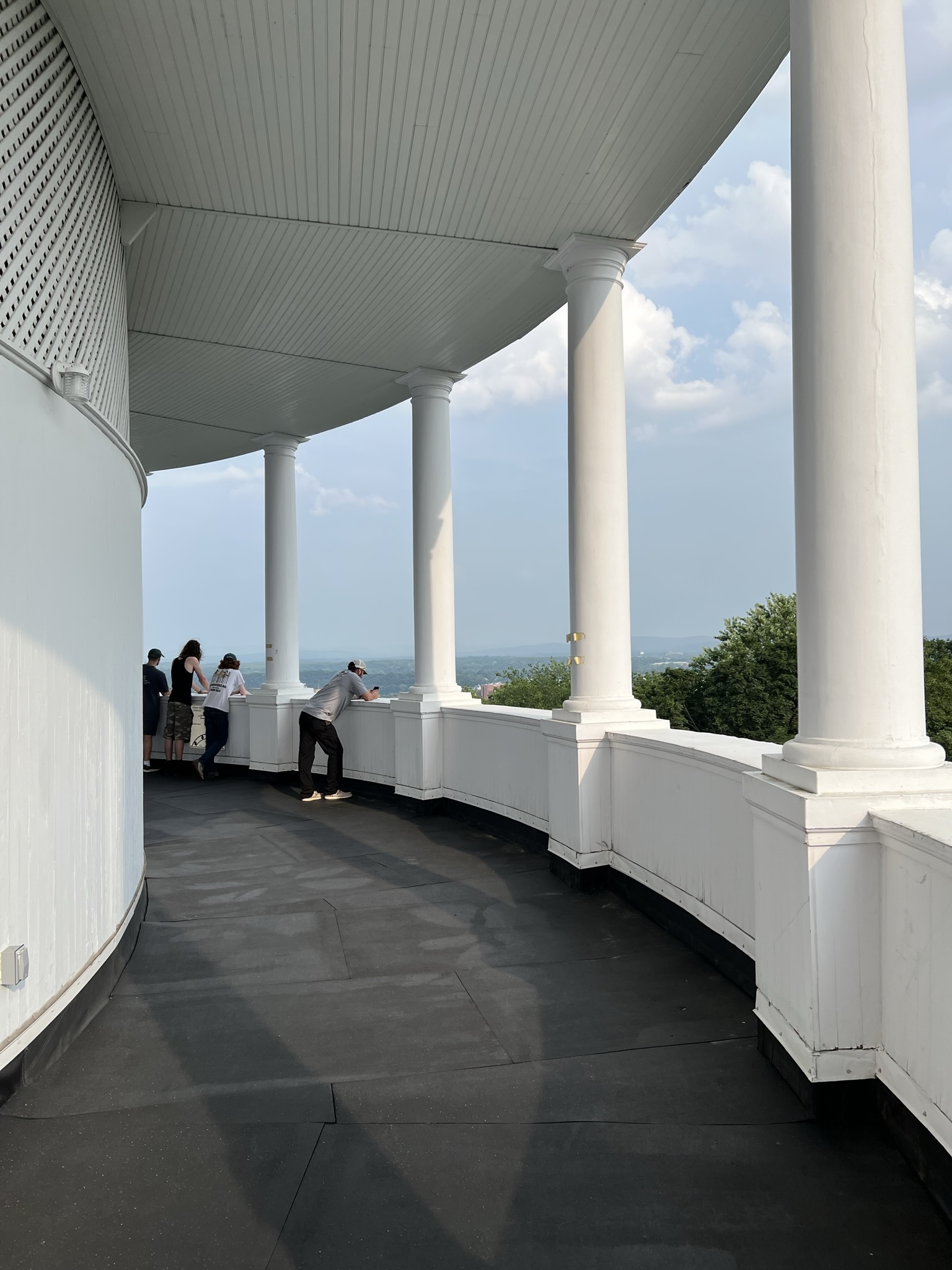 View along the curved colonnaded observation deck at the top of the Bangor Standpipe, with visitors looking out over a panoramic view of Bangor and the surrounding landscape.