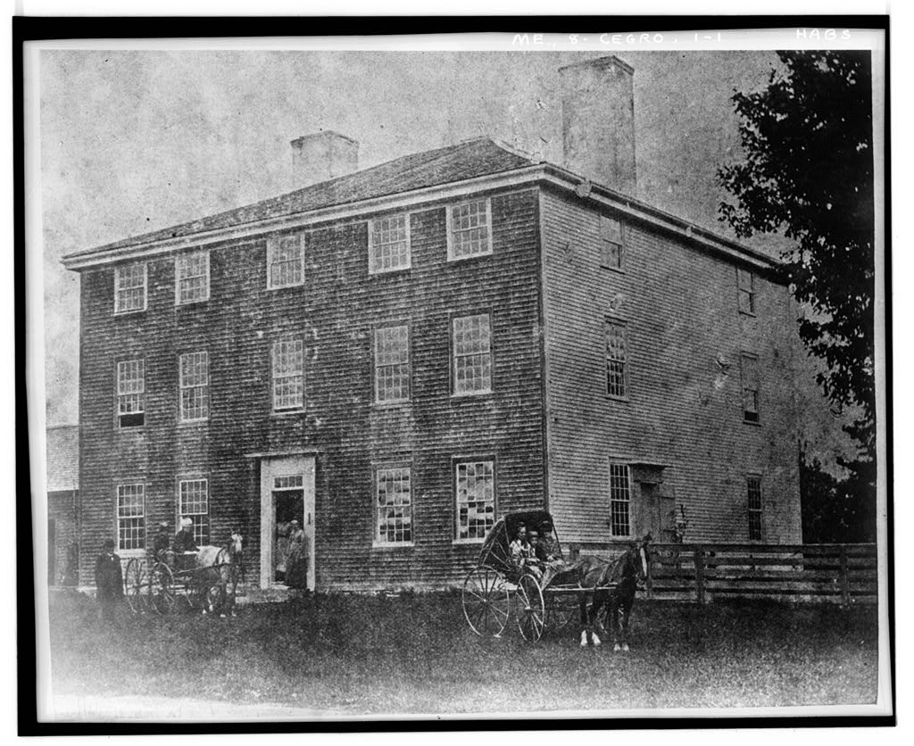 Early archival photo of the Pownalborough Court House, showing the three-story shingled building with horse-drawn carriages and figures gathered at the entrance.