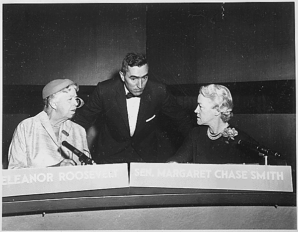 Two women seated at a desk with a man in between them.