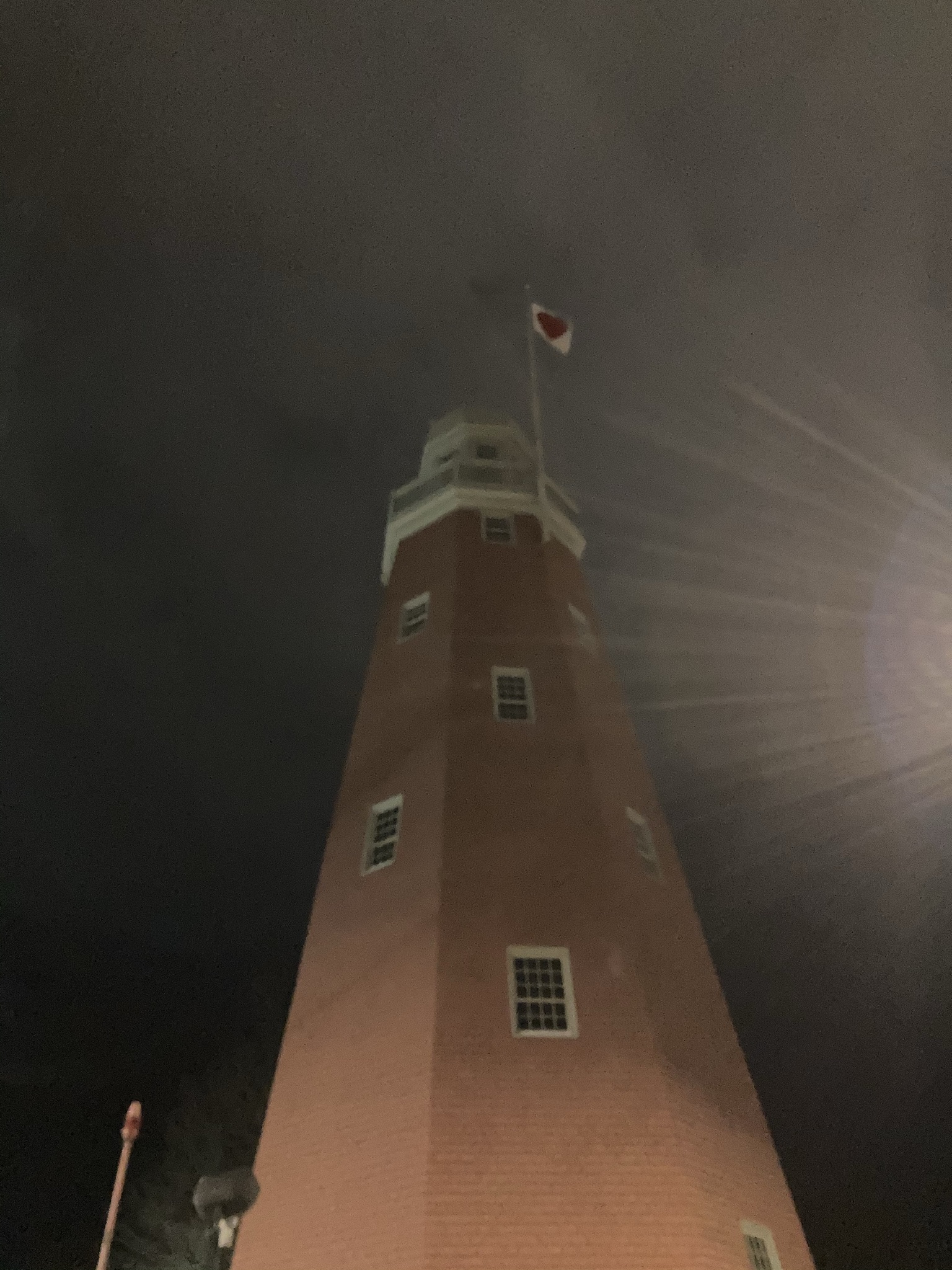 A nighttime view looking up at the Portland Observatory with a small heart-shaped flag flying from its top.