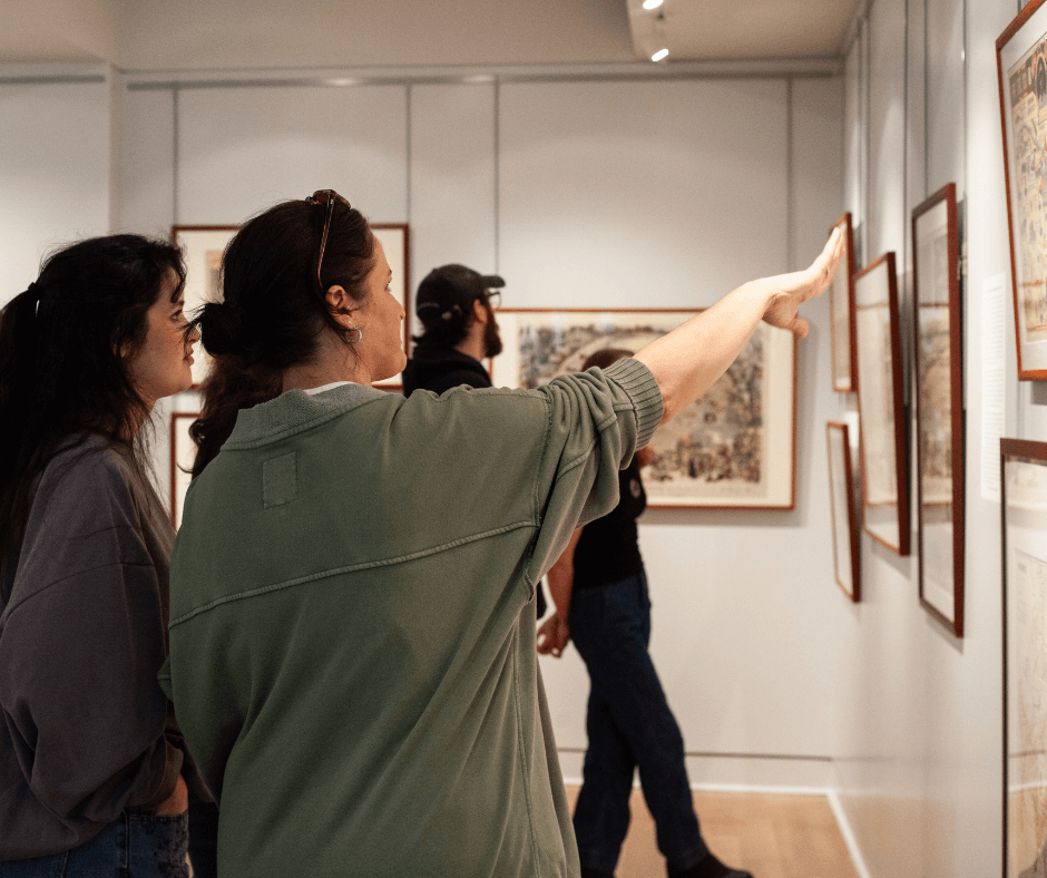 Visitors browsing framed historical maps on display in the Osher Map Library's public gallery.