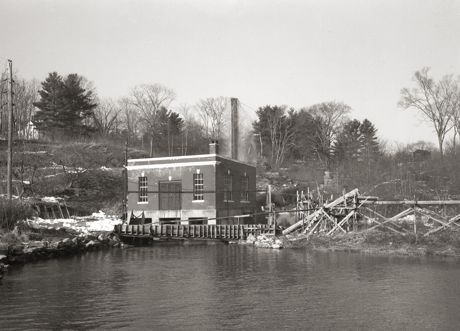 A brick building next to a dam on a river