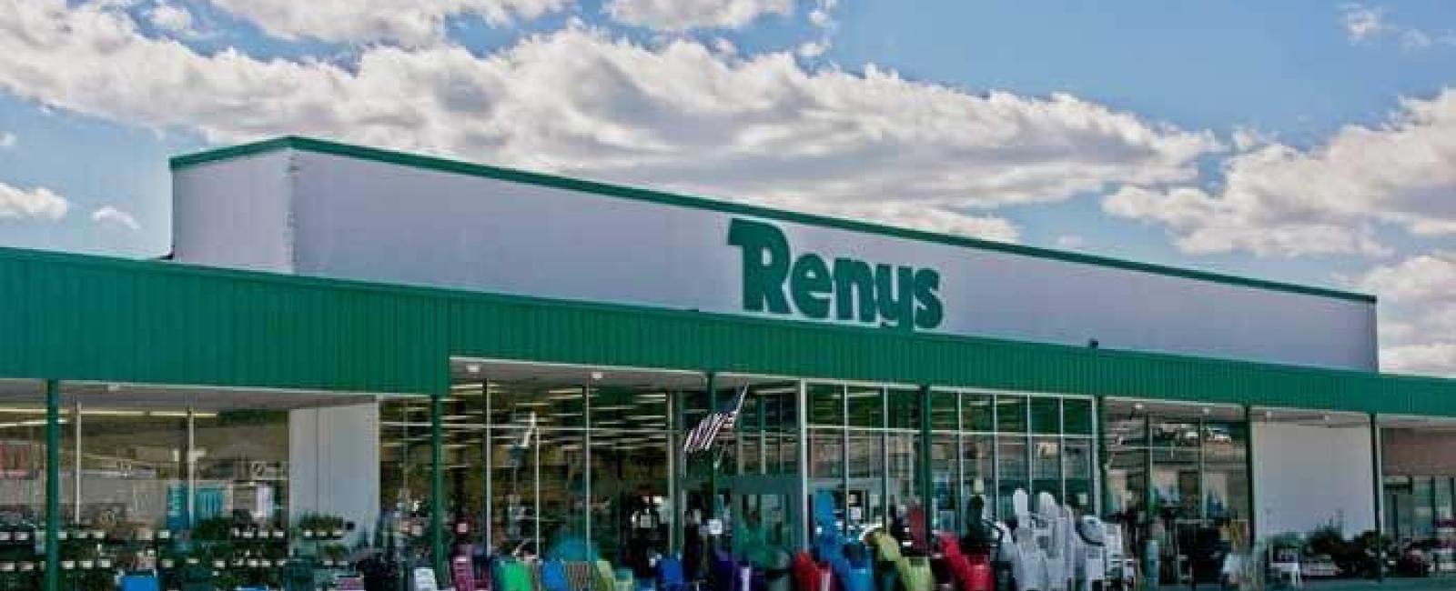 Renys storefront with a green and white sign, wide glass windows, and outdoor patio furniture displayed for sale under a blue sky.